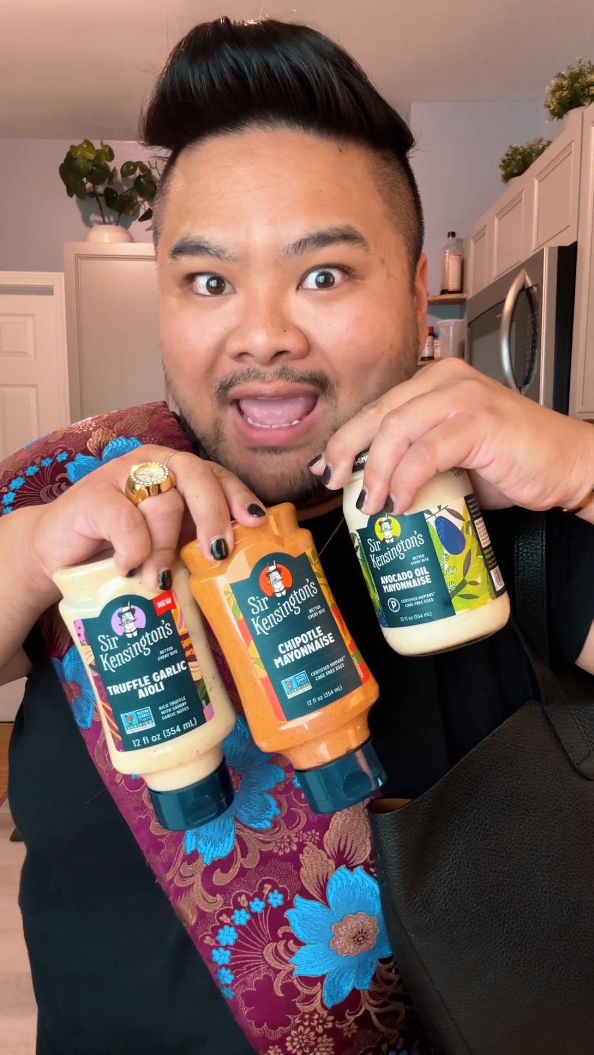 I hold Sir Kensington’s Truffle Garlic Aioli, Chipotle Mayonnaise, and Avocado Oil Mayonnaise while making an animated expression in my kitchen.