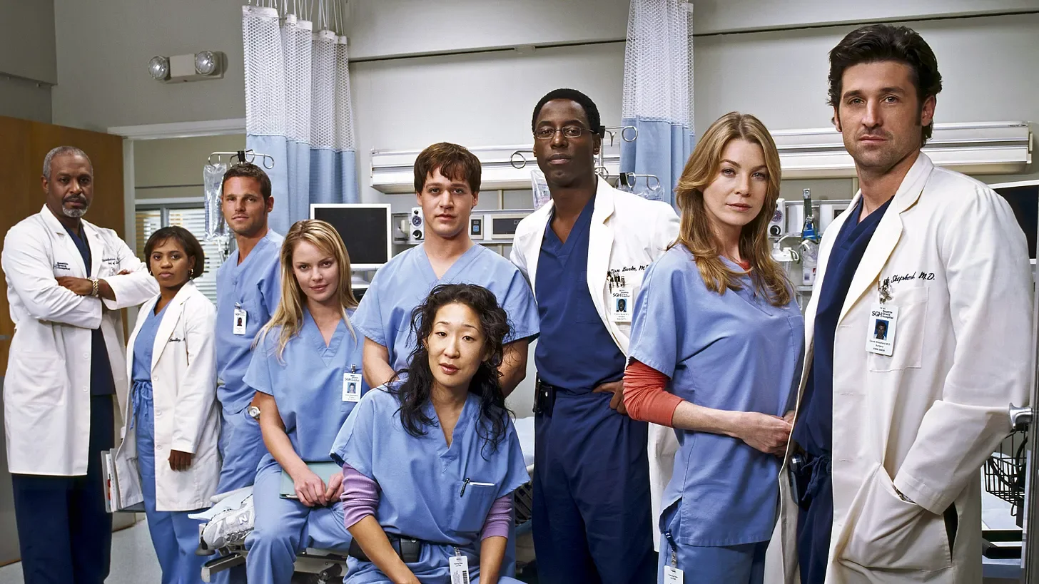 The original Grey’s Anatomy cast poses in a hospital room.