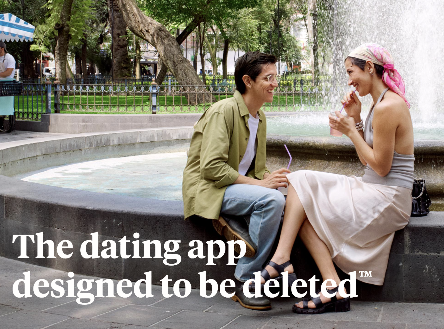 Two people sit beside a fountain in Hinge’s campaign image, with the text “The dating app designed to be deleted.”