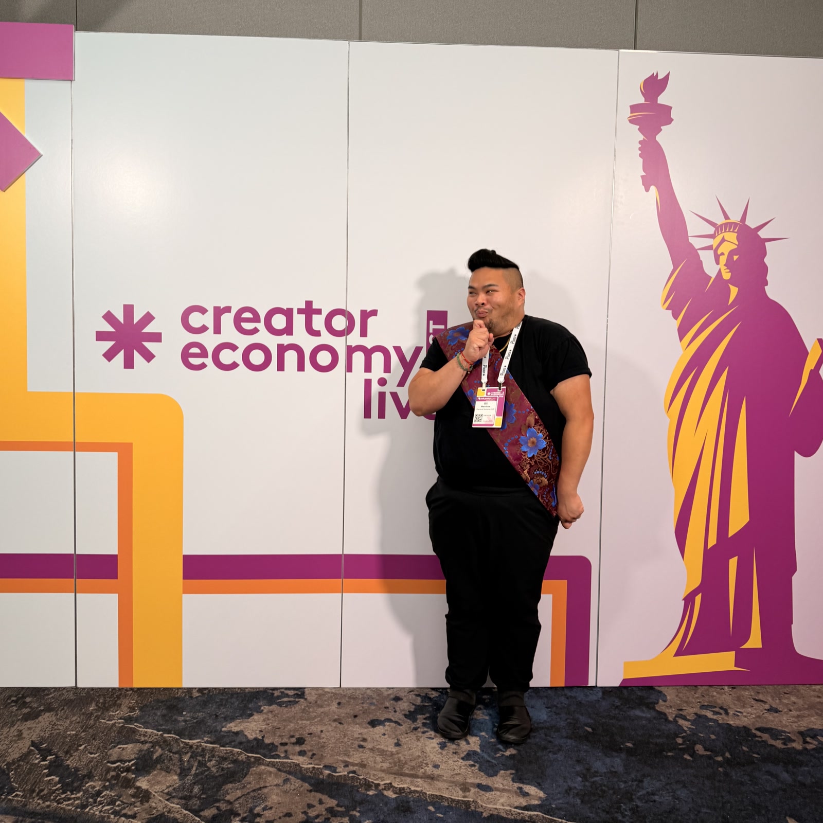 RV Mendoza standing beside the Creator Economy Live East event wall in New York.