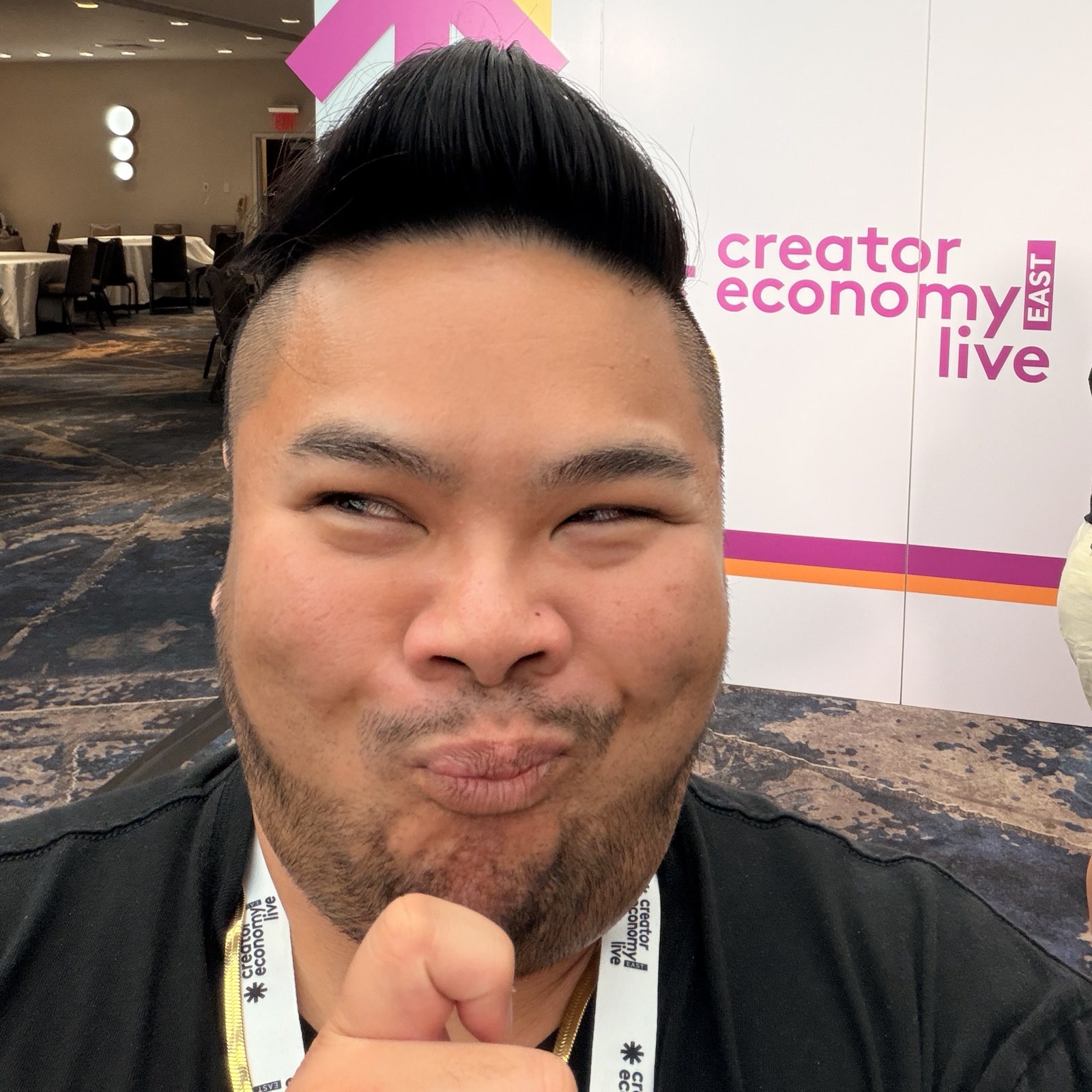 RV Mendoza smiling in front of the Creator Economy Live East event wall.