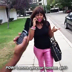 A woman on a phone while someone gestures to ask for her number