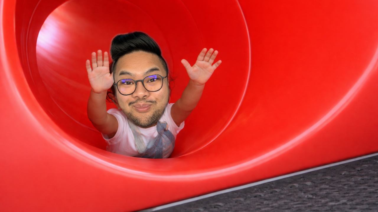 RV Mendoza reaches upward while sliding through a bright red tube slide.