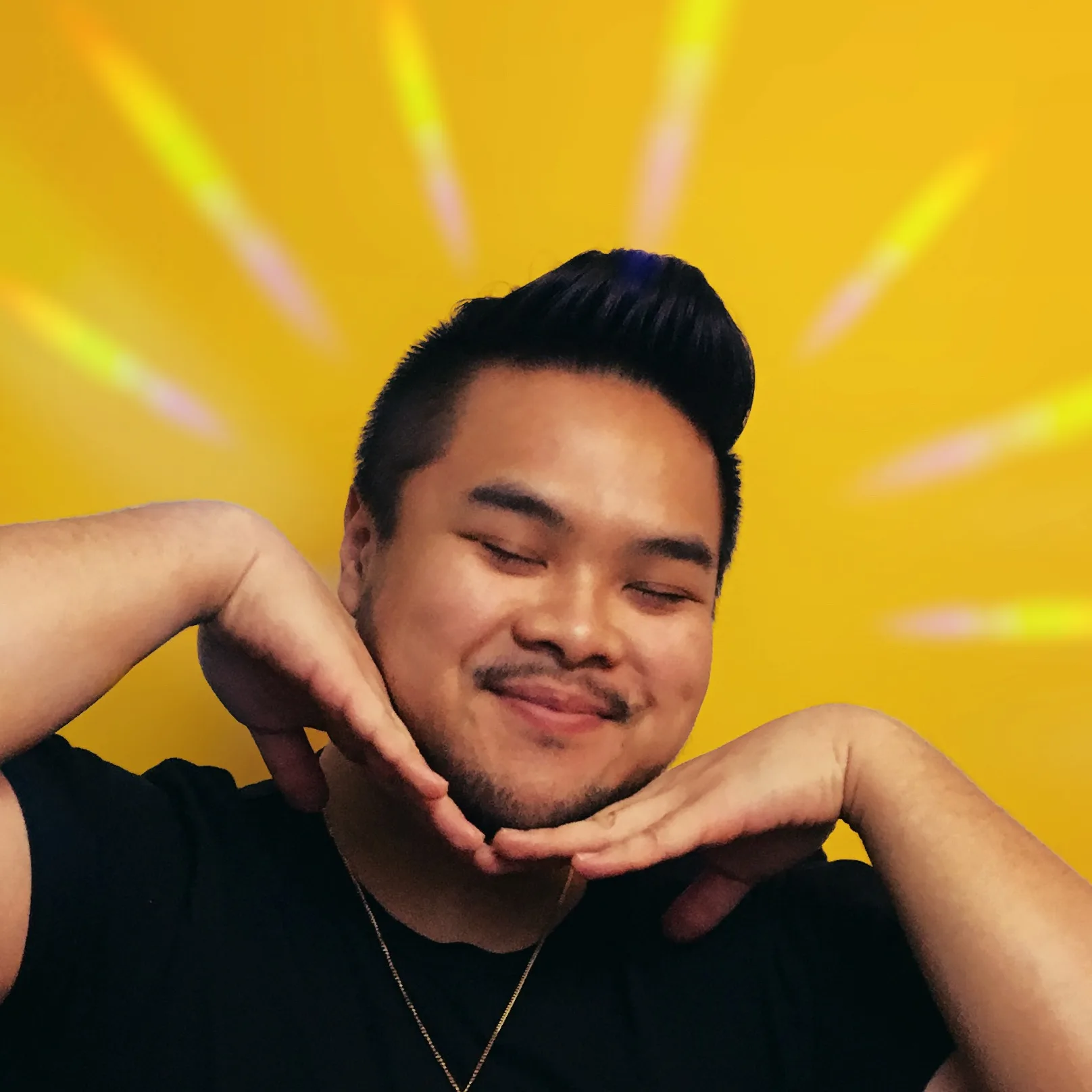 RV Mendoza smiling with chin resting on both hands against a bright yellow background.